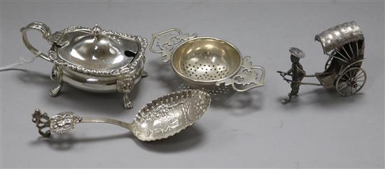 A silver mustard pot, a late 19th century continental spoon, a sterling silver model of a rickshaw and a silver tea strainer.